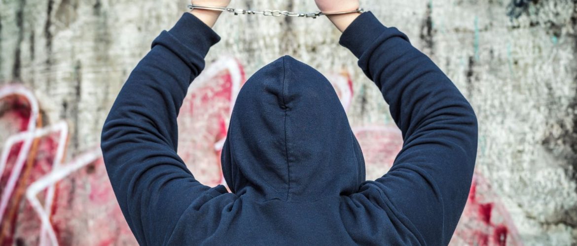 handcuffed-man a man in a hoodie with his arms raised and handcuffed