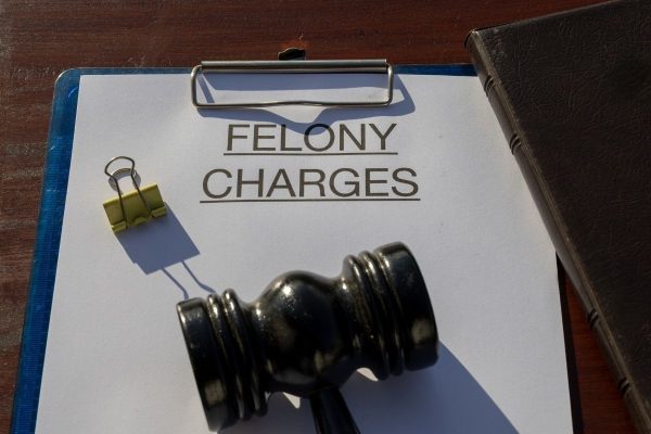 a gavel on top of a folder labeled "felony charges"
