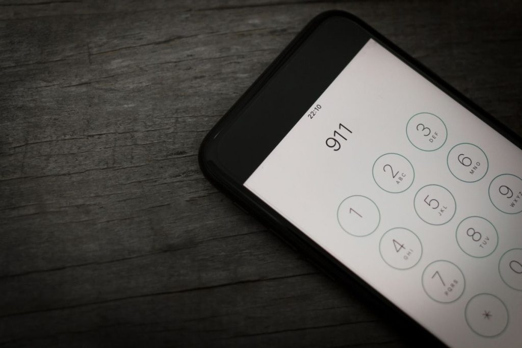 an iphone on a wood table with 911 dialed