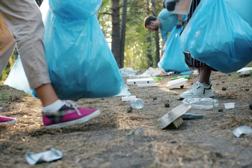 the feet of a group of volunteers picking up trash from a beach