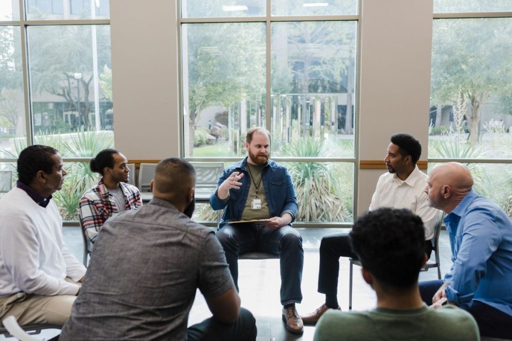 a group of men sitting in a circle participating in group therapy