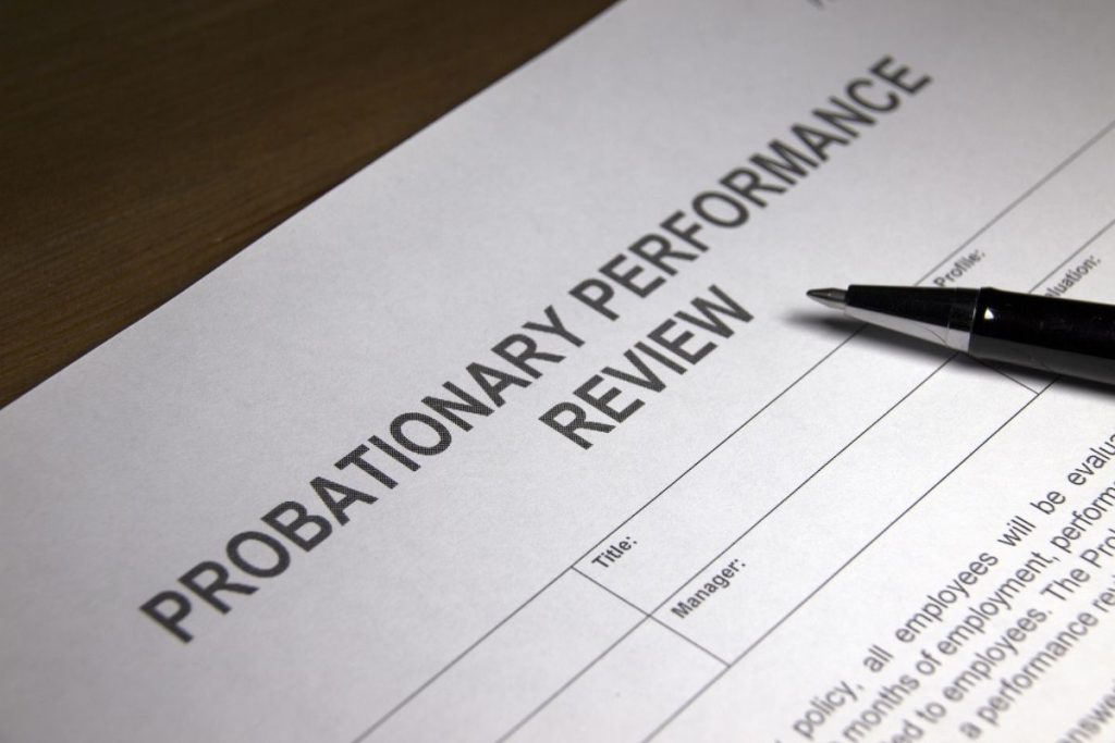 a close up of a probationary performance review document and pen