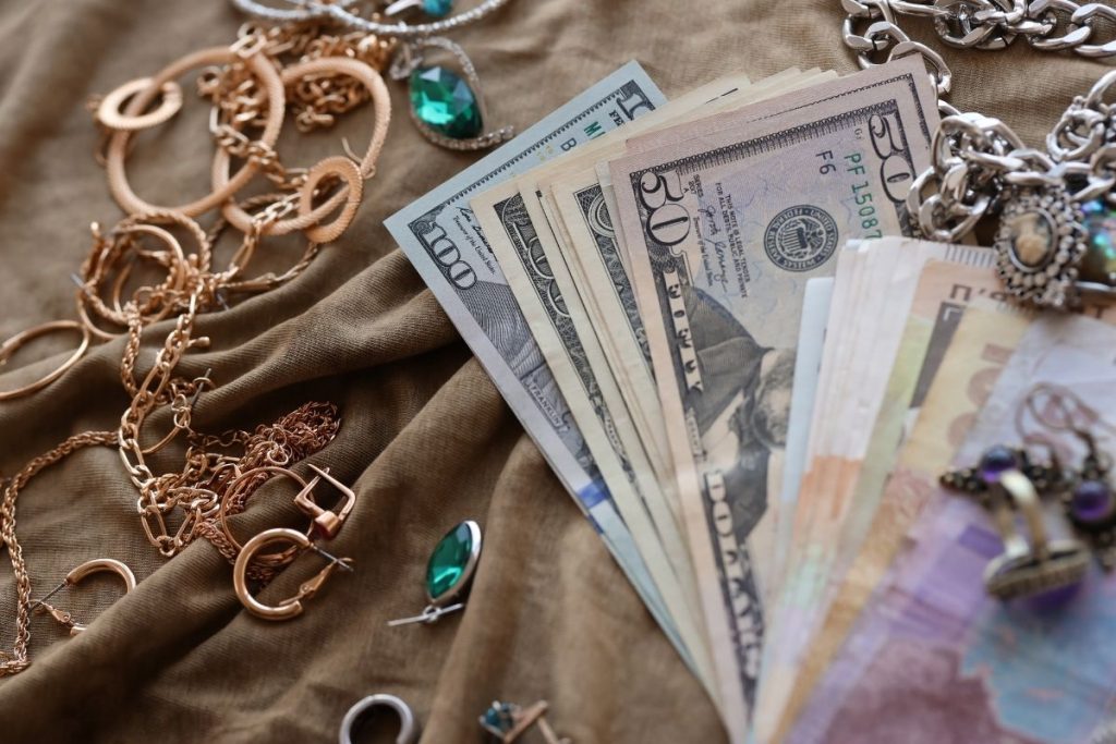 a stack of cash next to various jewelry