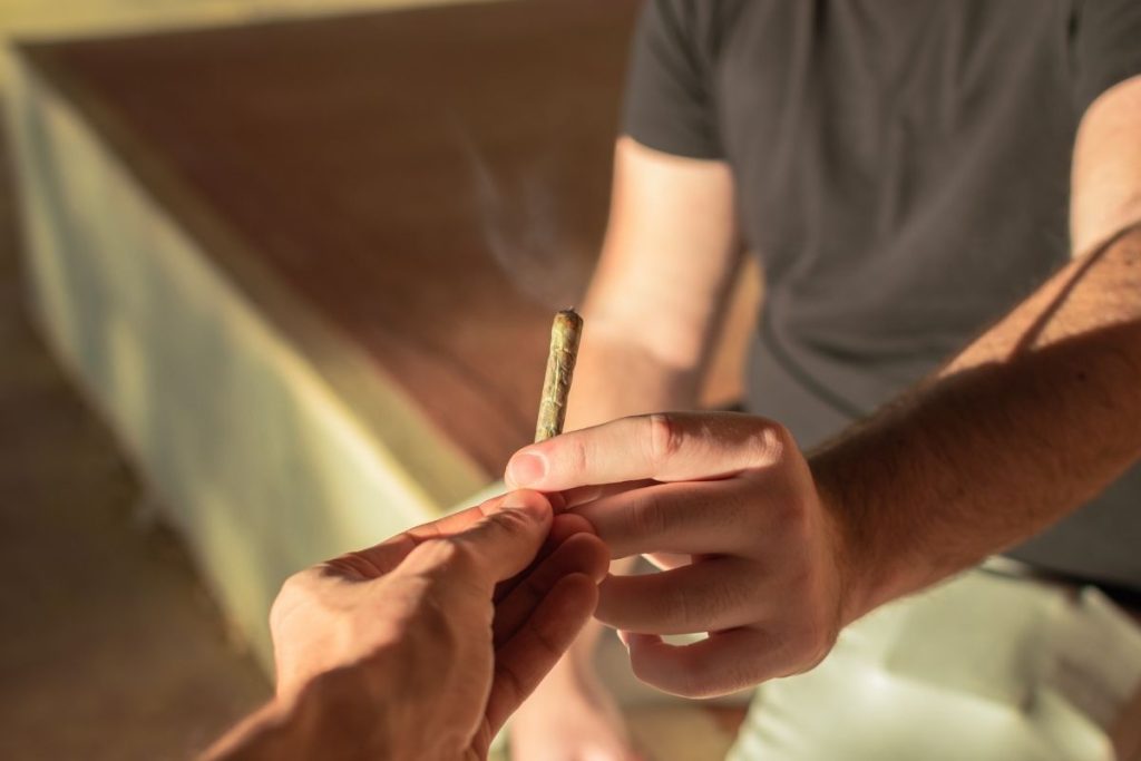 a close up of a joint being passed between two young men
